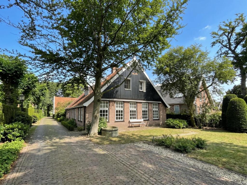 a house with a tree and a brick driveway at De Binnenhof in Vriezenveen