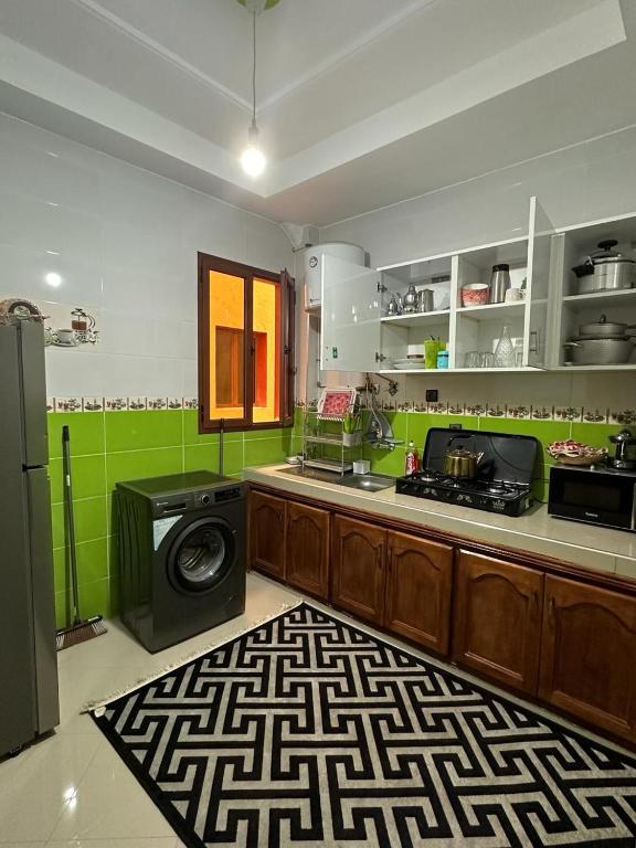 a kitchen with green walls and a stove and a microwave at Jannat Résidence in Ouarzazate