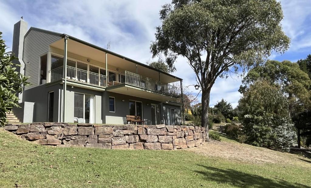 a house on a hill with a stone wall at The River House in Merrijig
