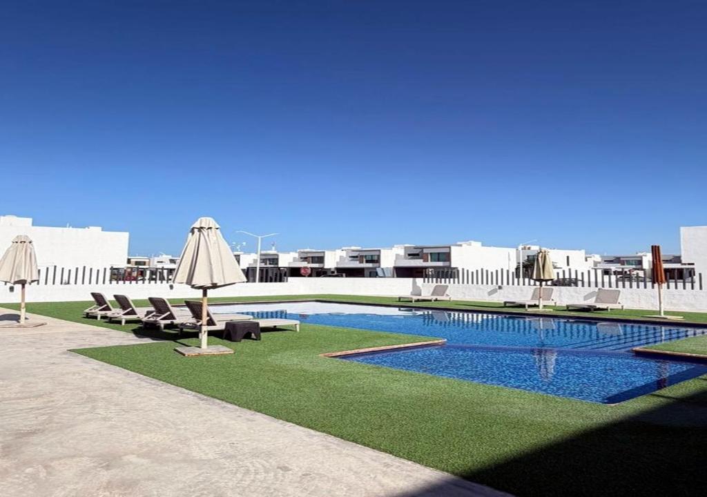 a swimming pool with chairs and umbrellas on a building at Casa moderna, 3 recámaras, alberca, La Paz BCS in La Paz
