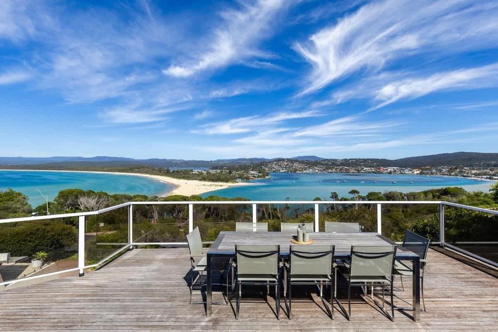 a table and chairs on a deck with a view of the ocean at Bula Vista in Merimbula