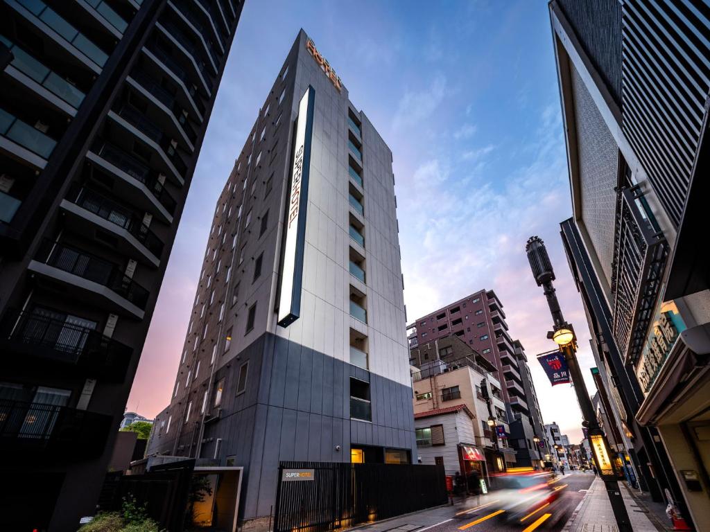 a tall building on a city street with buildings at Super Hotel Shinagawa Shinbanba in Tokyo