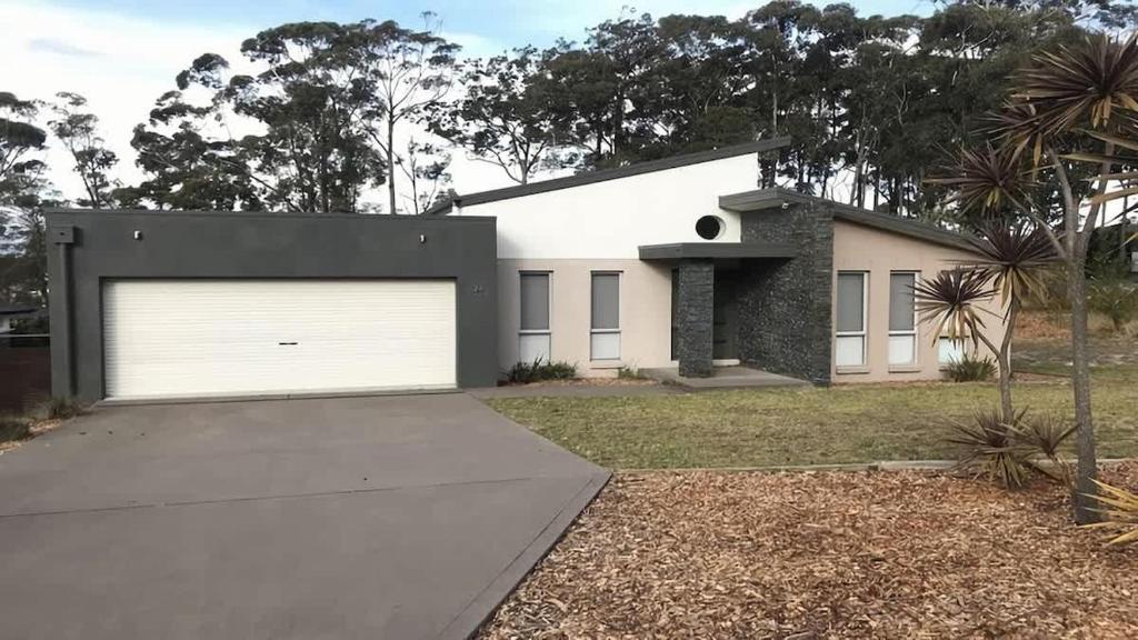 a white house with a garage at Turaroo in Tura Beach