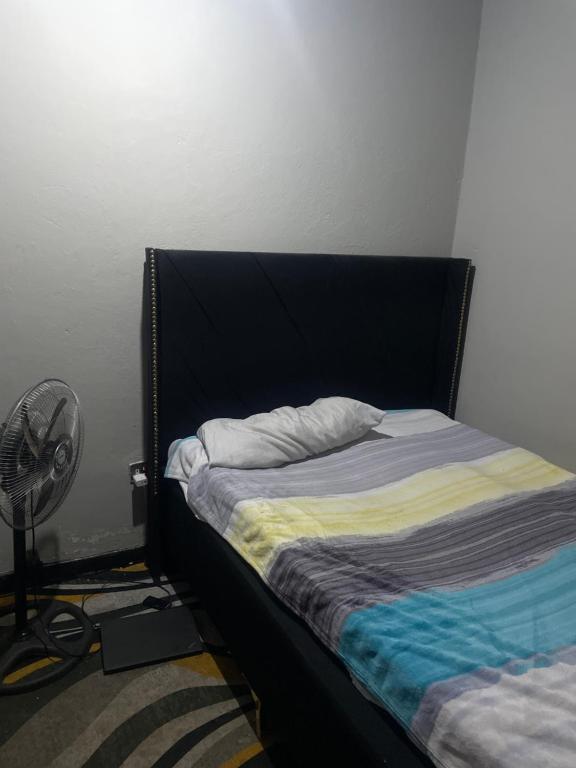 a bed with a black headboard next to a fan at Kaunda Home in Blantyre