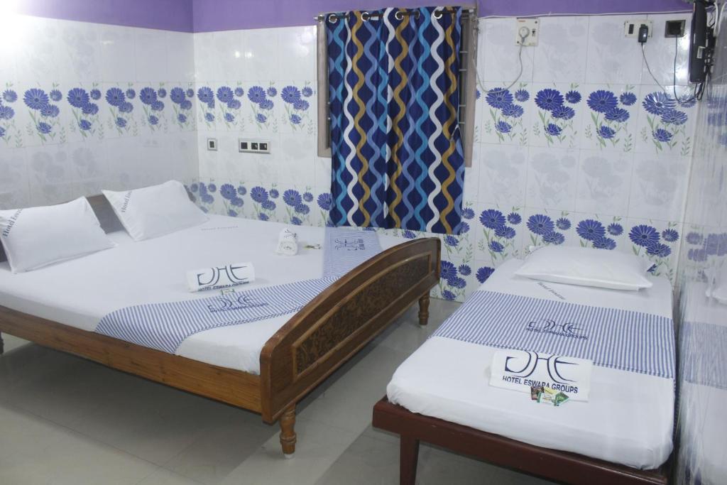 two beds in a room with blue and white at Hotel Eswara Temple Stay in Kumbakonam