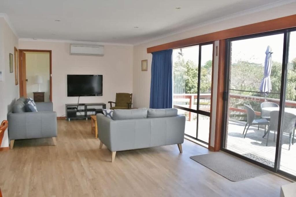 a living room with a couch and a television at Laura's Pambula Beach in Pambula Beach