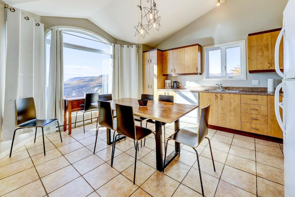 a kitchen with a table and chairs and a large window at 2CH - Fireplace Panoramic View - Upper Unit in Petite-Rivière-Saint-François