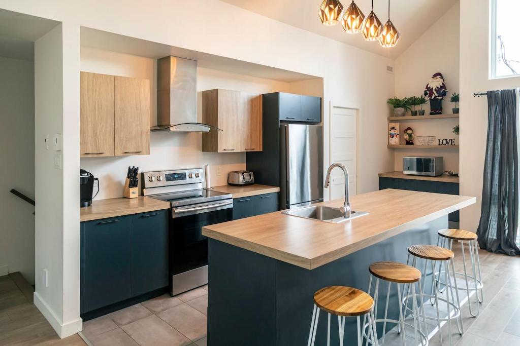 a kitchen with blue cabinets and a kitchen island with stools at 2CH Relaxation Spa Sauna BBQ Wi-Fi in Pont-Rouge