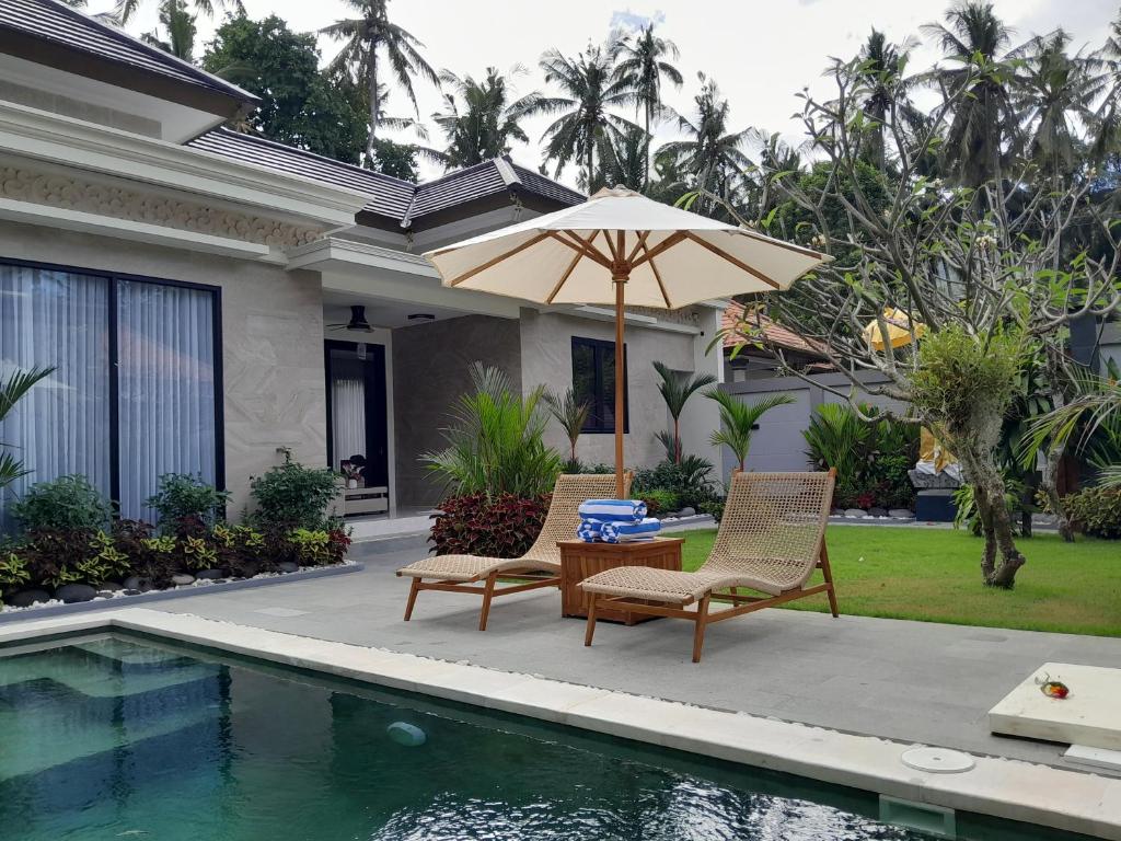 a patio with two chairs and an umbrella next to a pool at Villa KARISMA Candidasa in Candidasa