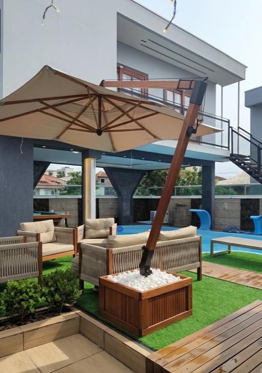 a patio with benches and an umbrella on the grass at Hotel Pousada Litorânea in Tijucas
