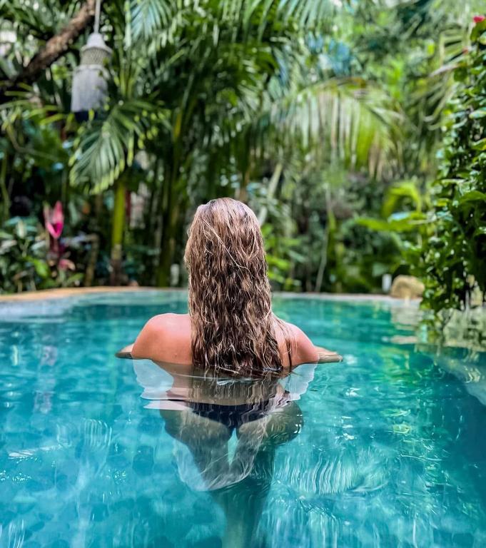 a woman sitting in the water in a swimming pool at ANAND Ecoaldea in Puerto Morelos