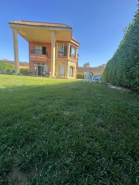 a large house with a large yard with grass at Stand alone Villa at Blumar North coast -SIDI ABD ALRAHMAN in El Alamein
