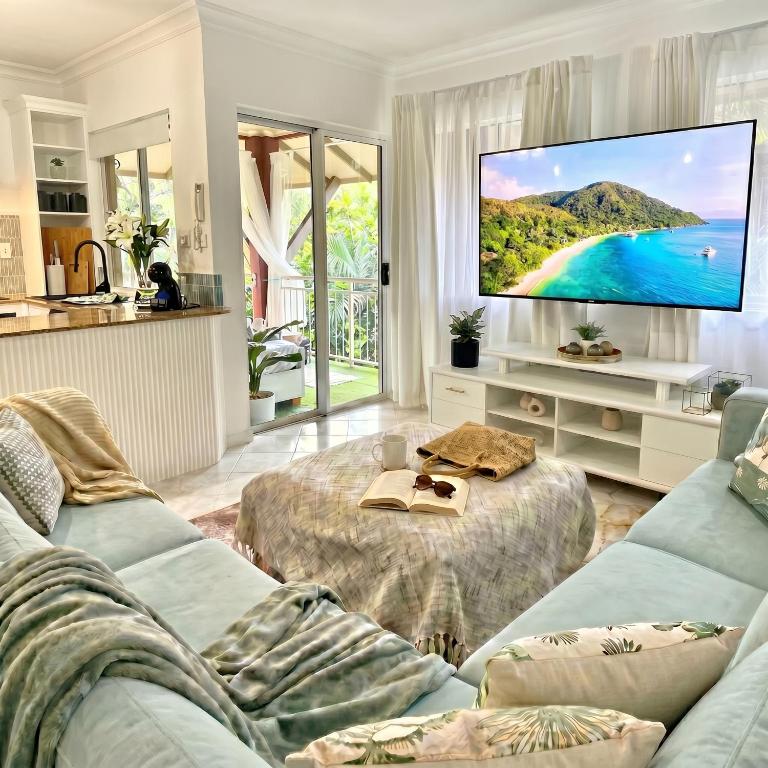 a living room with a couch and a large screen tv at Luxury 2 Bedroom apartment, Treetop views, Resort with 4 swimming pools in Cairns North