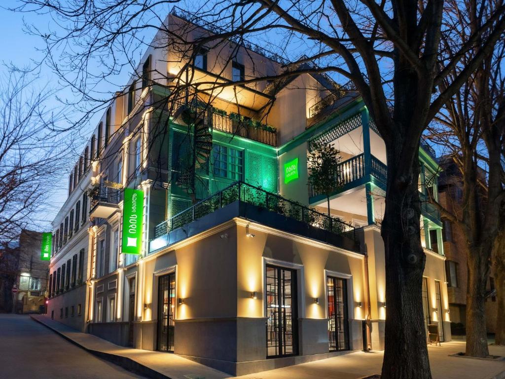 a white building with a green sign on it at ibis Styles Old Tbilisi in Tbilisi City