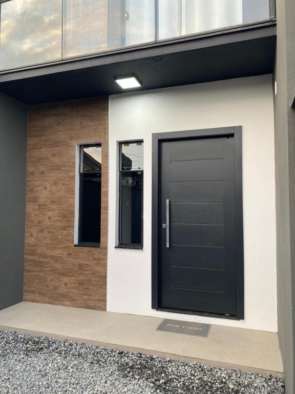a black door on the side of a house at Casa nova e ampla, completa para sua hospedagem in Joinville