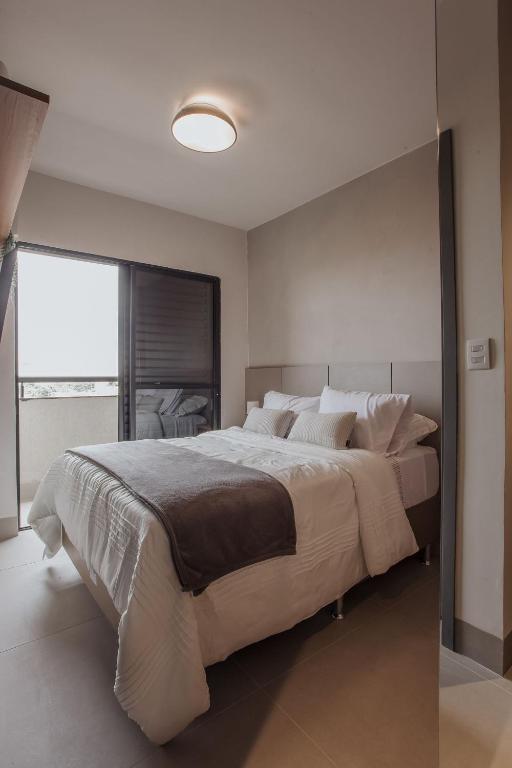 a bedroom with a large bed with a large window at Actual House in Uberlândia