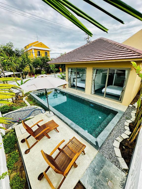 a swimming pool with two chairs and a house at LAA Maison in Hoi An