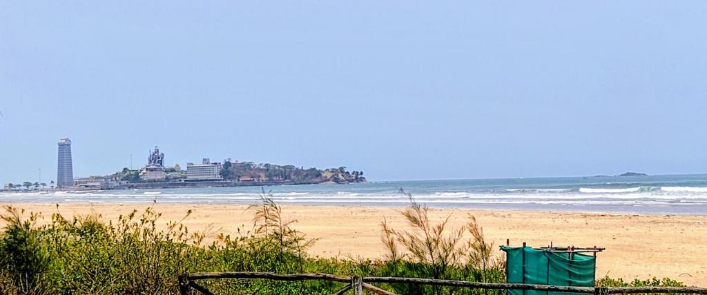 a beach with a building in the distance and the ocean at Nestle Sahayadri BeachFront Homestay Murudeshwar in Māvalli