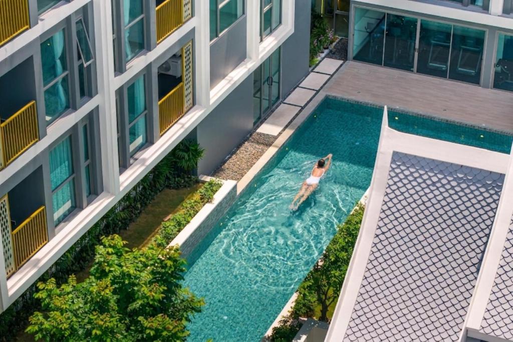 a woman swimming in a swimming pool in a building at Modern 2BR Apartment with Golf View in Laguna Phuket - Condo Ozone 108-156 in Laguna Phuket