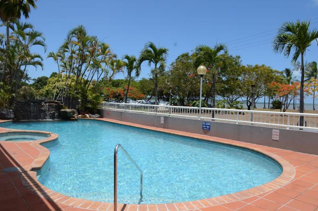 a swimming pool at a resort with palm trees at The Reef Motel in Cairns