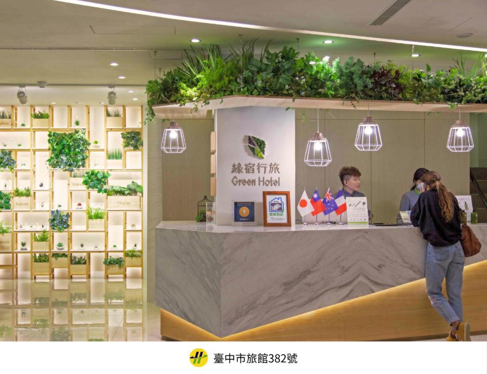 a person standing in front of a counter with plants at Green Hotel - West District in Taichung