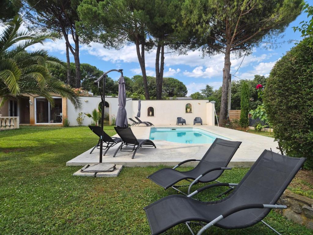 a group of chairs and an umbrella next to a pool at La Bastide Bleue in Anduze
