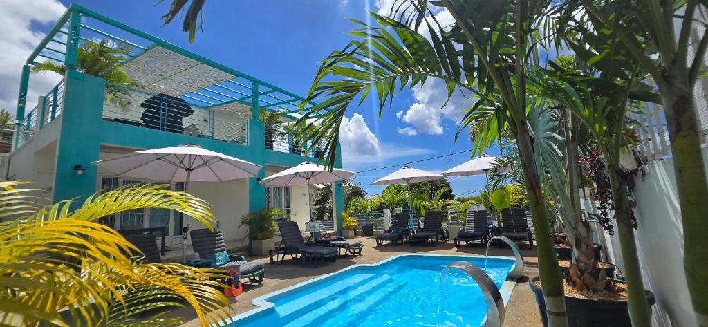 a pool with chairs and umbrellas next to a building at Abiki Mauritius with Tourism Authority Permit in Albion