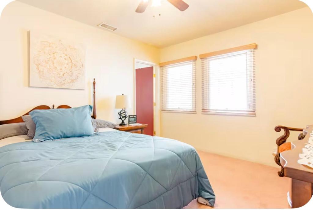a bedroom with a blue bed and two windows at Sacred Heart House in Montebello