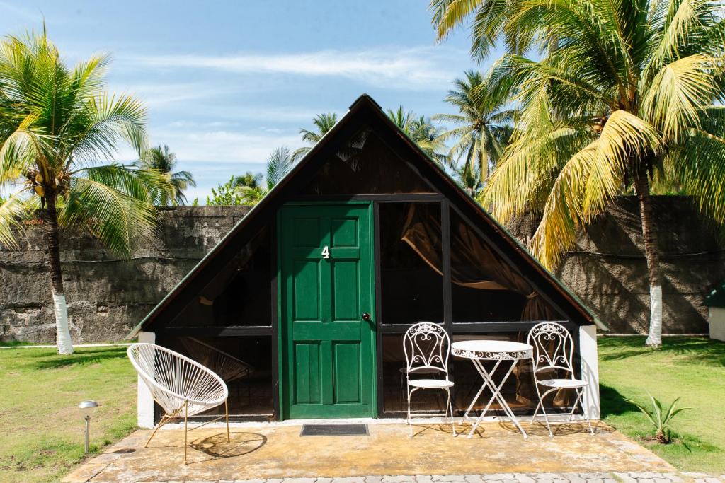 a house with a green door and chairs and palm trees at Hotel Los Olivos La Playa in Escuintla