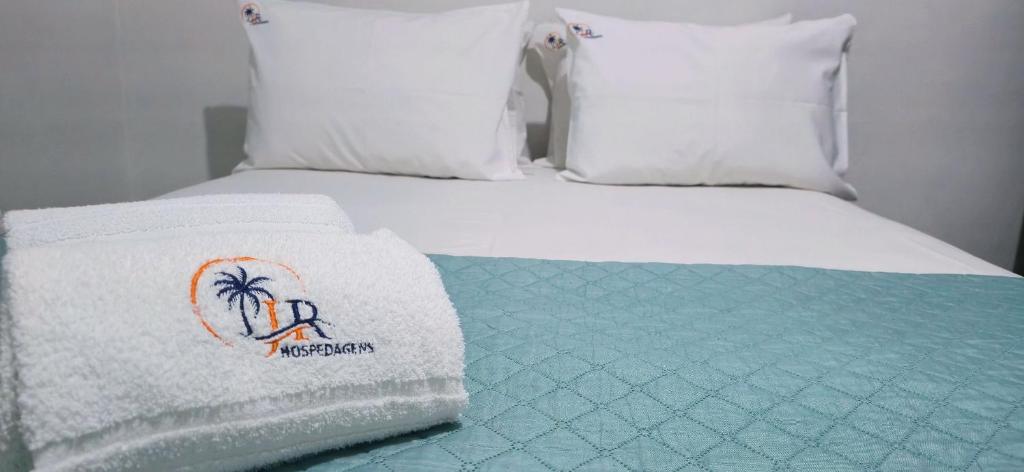 a bed with white sheets and a towel on it at Casa Cabugi Ponta Negra JR in Natal