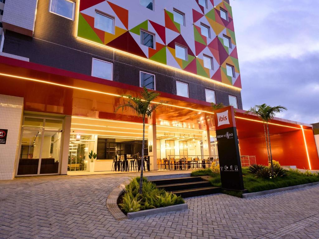 a facade of a building with palm trees in front of it at Ibis Caruaru in Caruaru