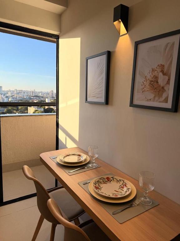 a dining room table with plates and glasses and a window at 818 - Standard Premium in Uberlândia
