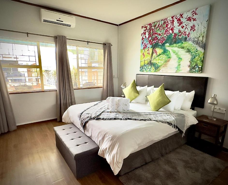 a bedroom with a large bed and a painting on the wall at Kliprand Guest House in Springbok