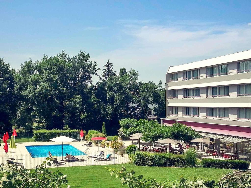 a hotel with a swimming pool next to a building at Mercure Brive in Ussac