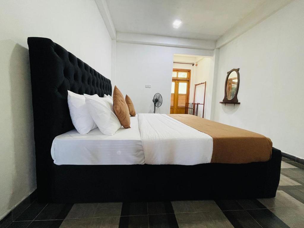 a bedroom with a large bed with a black headboard at Archwey Coco Ella in Ella