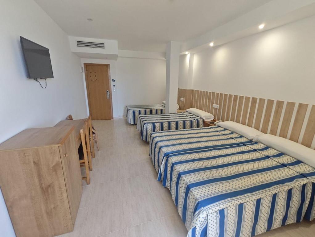 a room with two beds and a flat screen tv at Hotel Ría Mar 3 estrellas Superior in Villalonga