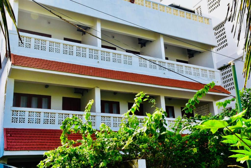 a building with white and red balconies and trees at Buddha Beach Hotel in Kovalam