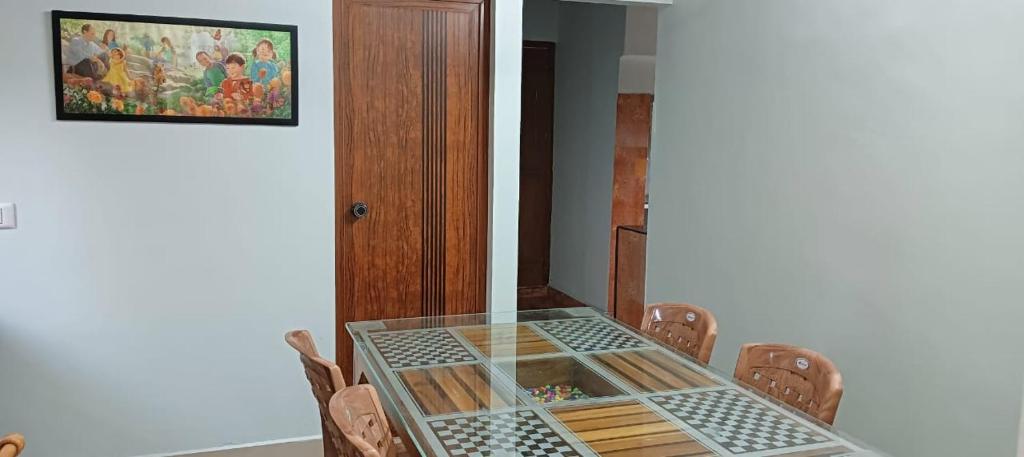 a glass table with chairs and a painting on the wall at Morning Glory in Vagamon