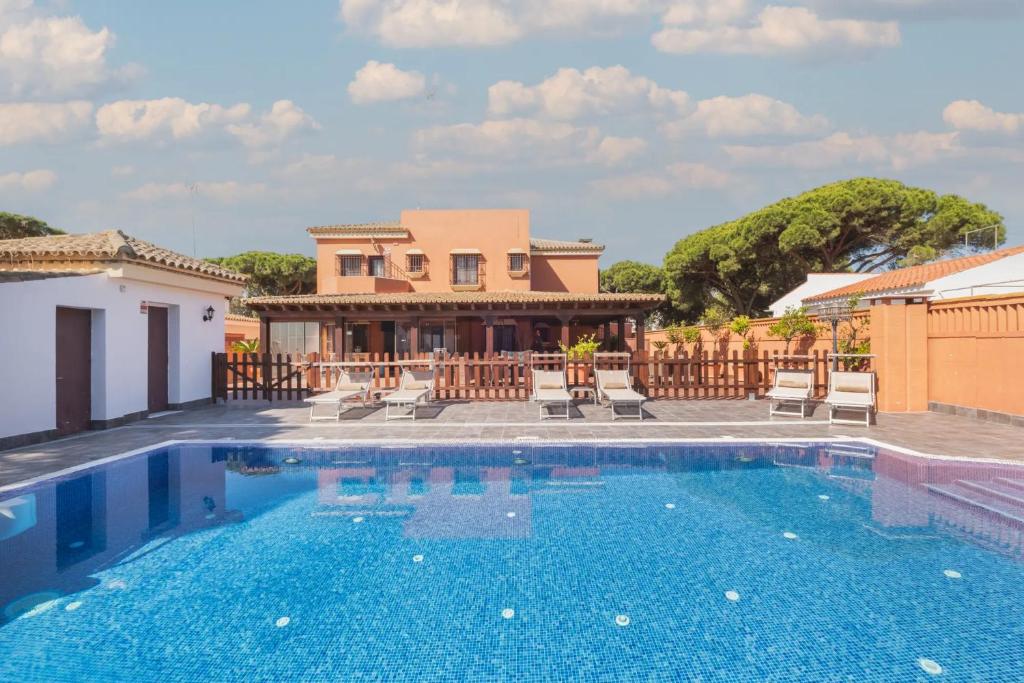 a villa with a swimming pool in front of a house at Hotel Amapola La Barrosa in Novo Sancti Petri