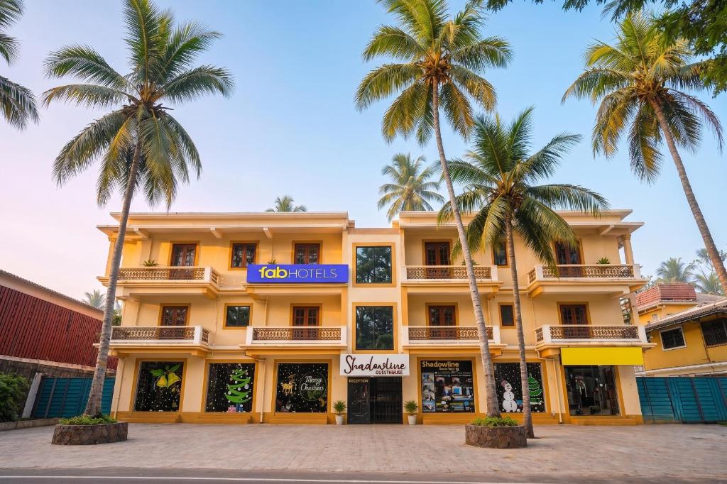 a yellow building with palm trees in front of it at FabHotel Shadowline in Goa
