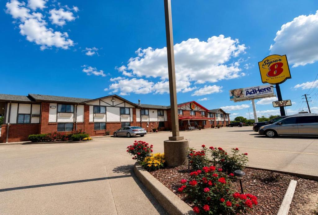 a hotel parking lot with a street sign and flowers at Super 8 by Wyndham Warrenton in Warrenton