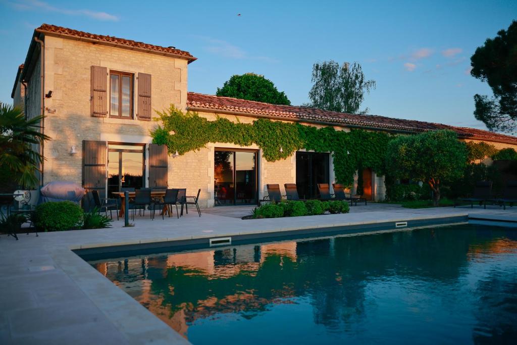 a house with a swimming pool in front of a house at Maison d'Hôtes Le Clos de Bacchus in Julienne