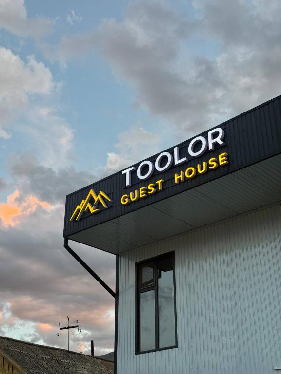 a toolnor guest house sign on top of a building at TOOLOR Guest House in Naryn