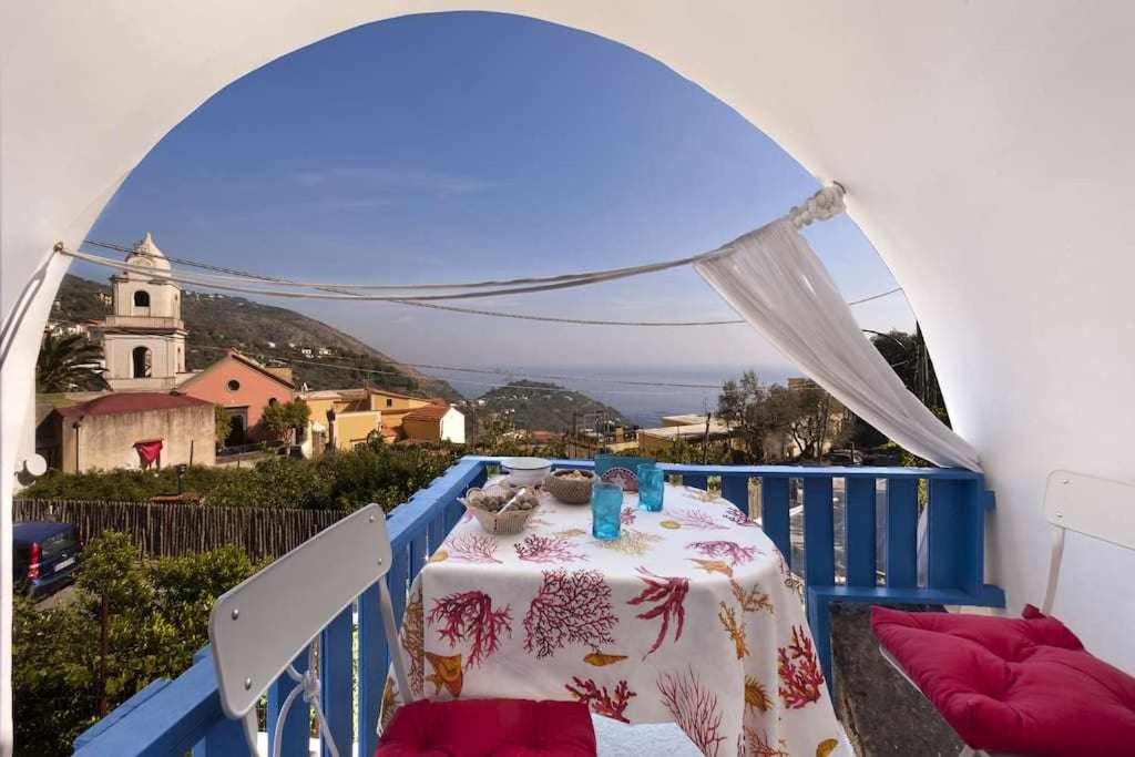 a table on a balcony with a view of a church at The Sirens House in Nerano