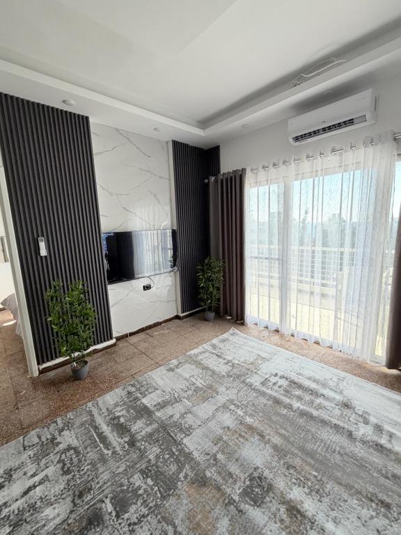 a living room with a television and large windows at Neue renovierte Wohnung mit Meerblick und große Balkon in tripoli ,Qalamoun in El Qalmoûn