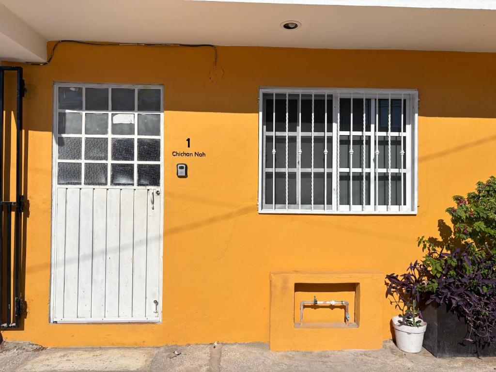 a yellow building with a white door and windows at Departamento chichan nah in Progreso