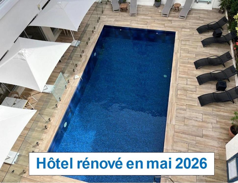 a swimming pool with umbrellas and a hotel remove an miami sign at Hôtel Le Yachtman, The Originals Collection in La Rochelle