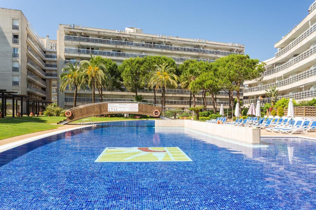 a large swimming pool with chairs and a building at Maria apartment in Blanes