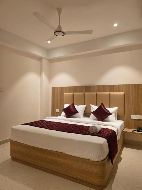 a bedroom with a large bed with red pillows at Kovil Vaasam in Tiruchirappalli