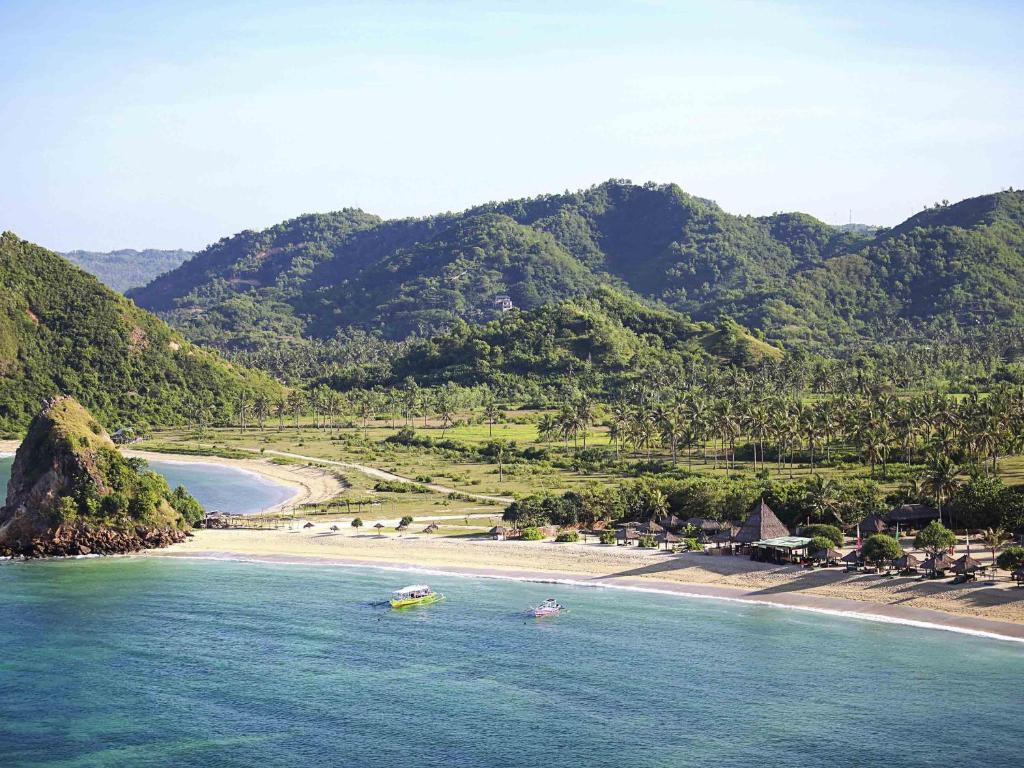 two boats in the water next to a beach at Novotel Lombok Resort & Villas in Kuta Lombok